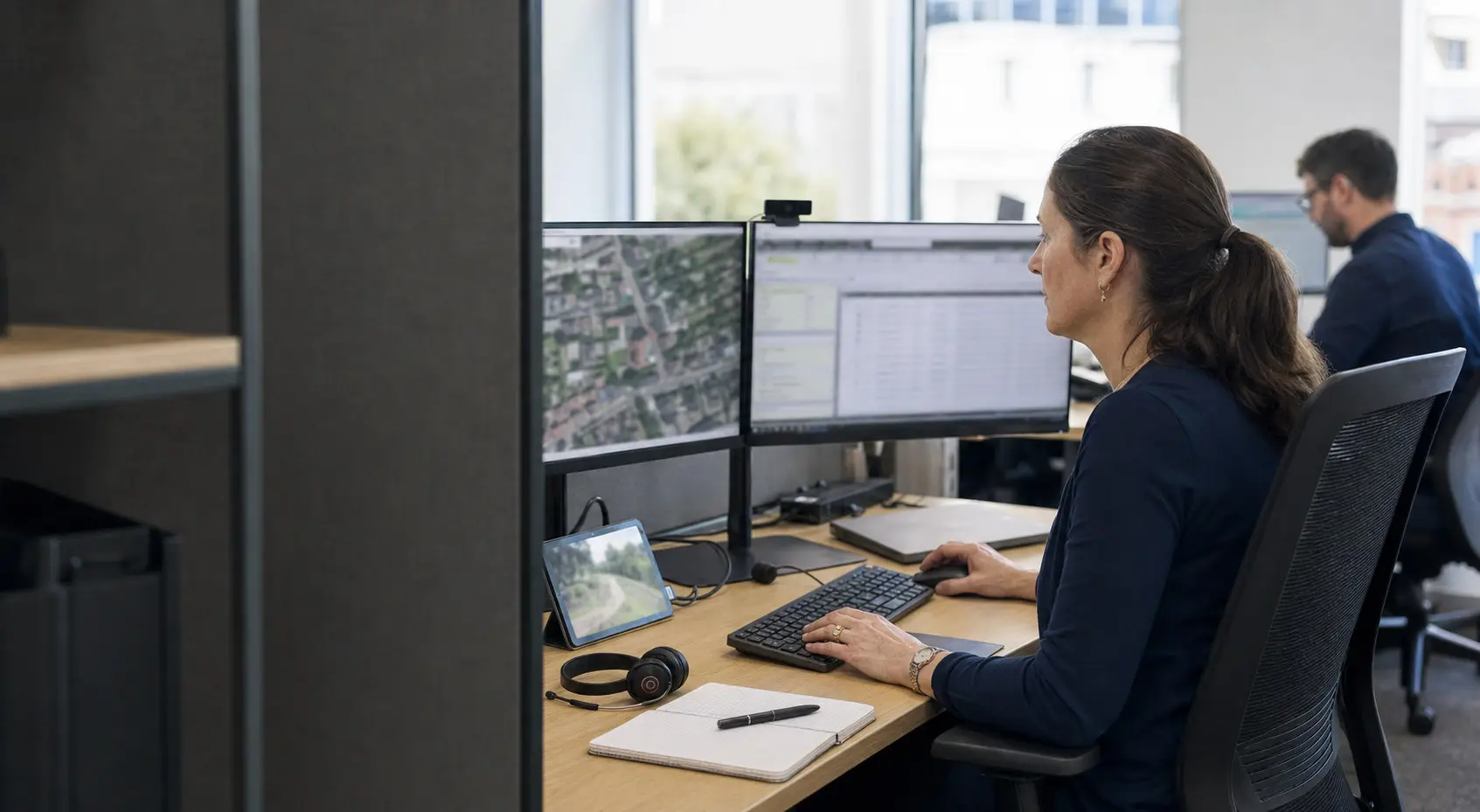 A GIS analyst compares spatial records and field evidence at a dual-monitor workstation.